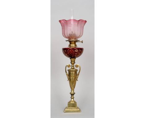 A Victorian gilt metal oil lamp
The etched red glass reservoir supported on an urn, the crimped shade with cranberry hue.  61