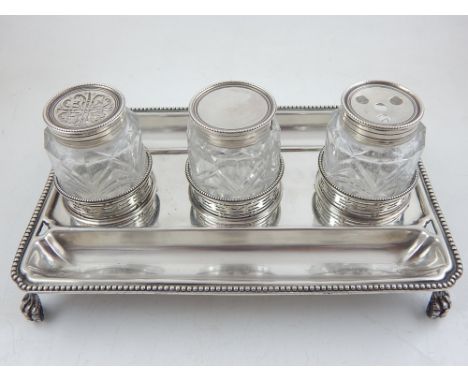 A George III rectangular silver standish, the beaded tray base incorporating two pen recess, housing three lidded cut glass j