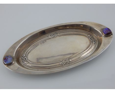 An Edwardian Art Nouveau silver pin tray, W. H. Haseler Ltd., Birmingham 1905, the oval embossed body inset two enamel bosses