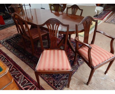 A George III style mahogany twin pillar dining table together with a set of six shield back dining chairs, two with arms.