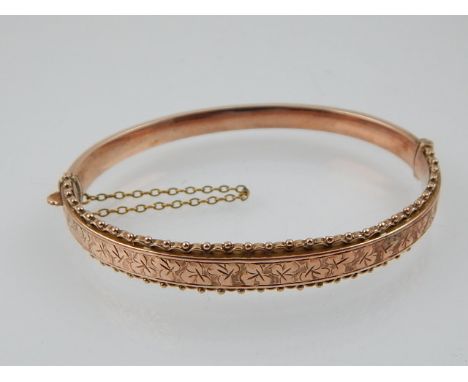 A 9ct gold bangle, Birmingham 1917, with diamond cut decoration and safety chain. 