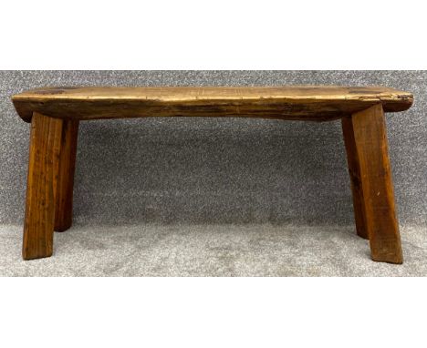 A primitive style tree trunk bench on square splayed supports. H.41 W.91 D.26cm