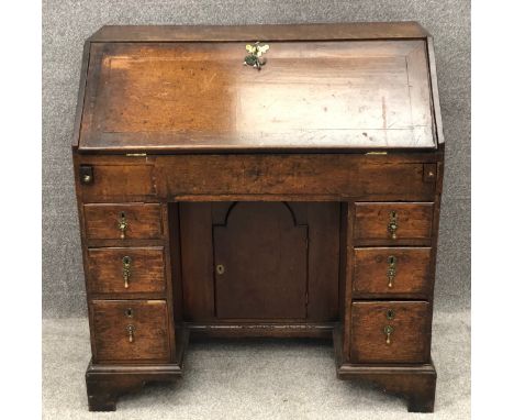 A Georgian country oak kneehole writing bureau with brass handles and a fitted interior on shaped bracket feet. H.102 W.97 D.