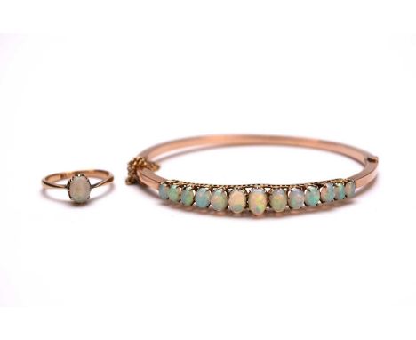 An early 20th century opal set hinged bangle, stamped '9ct', together with a single opal cabochon ring, stamped '18ct', ring 