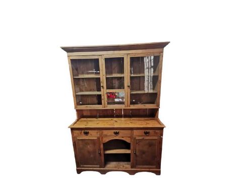 A large antique farmhouse pine kitchen dresser. The top splits from the bottom and has two glazed cupboards with a small mirr