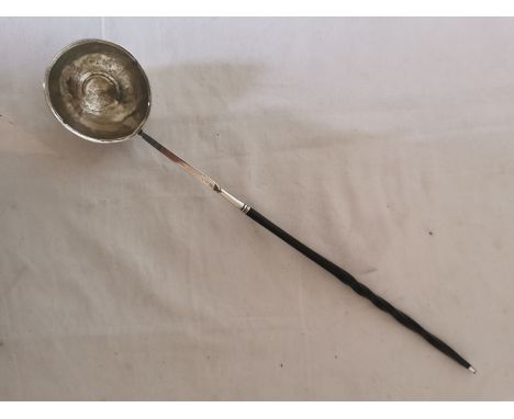 A Georgian white metal toddy ladle with twisted whale bone handle. The rounded bowl has a coin pressed in to the bottom. 37cm