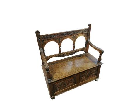 An 20th century carved oak settle/ monks bench with lifting seat and internal storage. 107cm wide and 47cm deep.