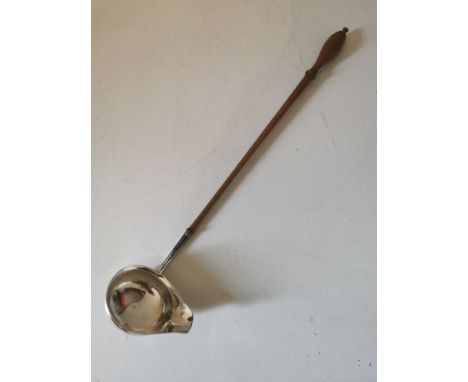 A Georgian silver single spouted punch ladle with a turned wooden handle. Hallmarked under the spout for: 'London 1787'. 35cm