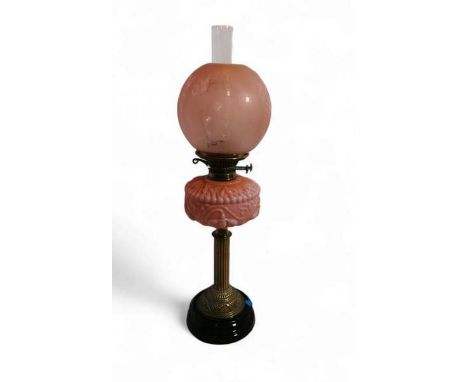 A Victorian oil lamp with a brass reeded column, pink opaline glass oil well and a globular pink etched glass shade, complete