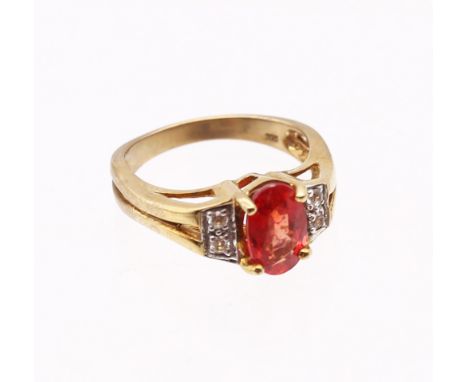 9ct Gold Ruby and Diamond Ring The ring consists of an Oval Brilliant Cut Orangish-Red Ruby that measures approx. 8.86mm x 5.