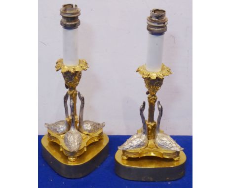 A pair of gilt-metal and silver-plated candlestick-style table lamps; each modelled as three swans with heads turned upwards 