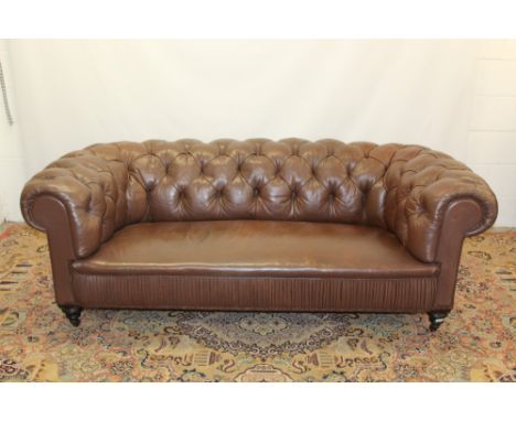 Late 19th / early 20th century Chesterfield sofa with button back brown upholstery, on turned feet and brass castors CONDITIO