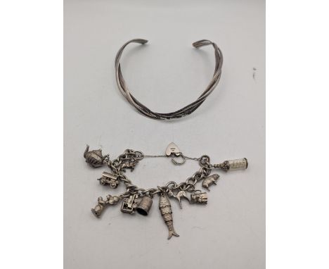 A silver charm bracelet with heart shaped padlock clasp with a selection of silver and white metal charms to include a fish, 