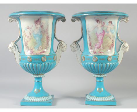 A LARGE PAIR OF CONTINENTAL LIGHT BLUE TWO HANDLED URN SHAPED VASES with heads as handles. 17ins high.