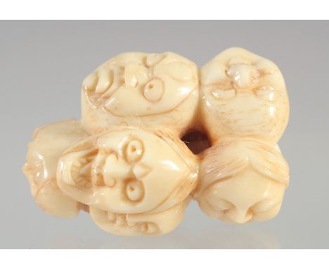 A CARVED BONE FACES NETSUKE.
