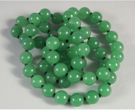 A STRING OF SIXTY GREEN JADE BEADS. 25ins long.