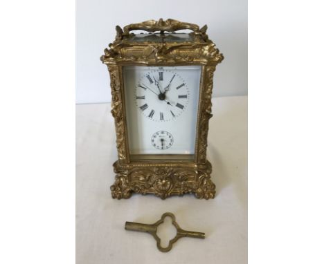 An ornate repeating carriage clock with enamel face and bevel edge glass panels. With key, in working order. Approx. 18cm tal