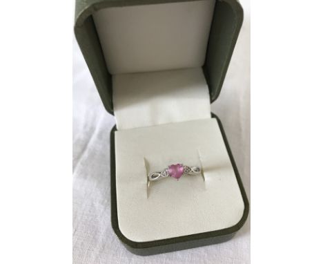 A 9ct white gold ladies dress ring. Set with central heart shaped pink sapphire and a small diamond to each shoulder. Ring si