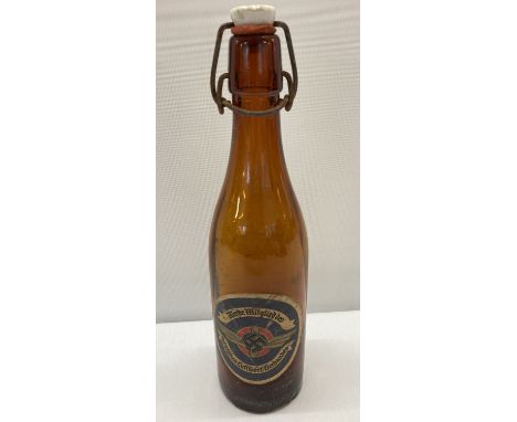 A WWII style brown glass beer bottle with German paper label and ceramic stopper.  Approx. 28cm tall.