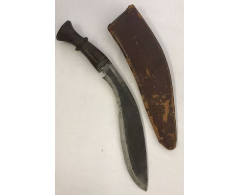 A vintage wooden handled Kukri with leather scabbard. Wooden handle has twisted carved design. Leather shows age related wear