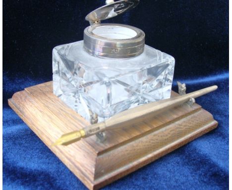 Silver-mounted cut glass inkwell with lid, on oak base, complete with silver dip pen.The base inscribed underneath on a white