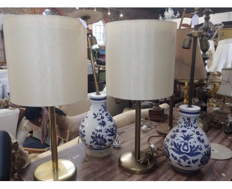 A PAIR OF BLUE AND WHITE CERAMIC LAMP BASES together with a pair of brass lamp bases (rust spots)