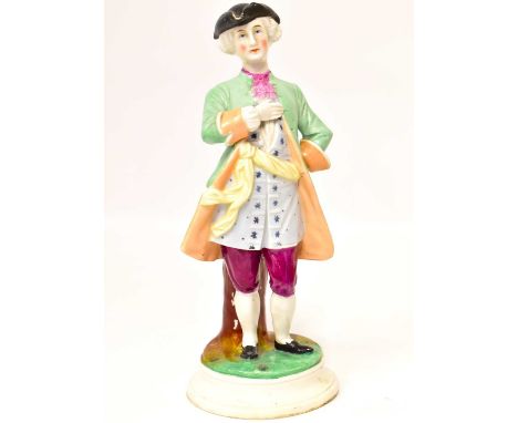 A 19th century tall Staffordshire pottery figure of a dandy man, with tricorne hat, green coat and patterned waistcoat, leani