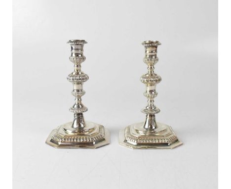K. M. SILVER; a pair of Elizabeth II hallmarked silver candlesticks with knopped stems, and spreading square section base wit