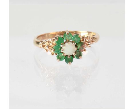 A 9ct gold cluster ring set with opal and emeralds, with stylised shoulders, stamped '375', size R 1/2, approx. 3g.