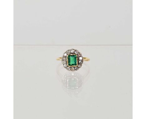 A yellow metal ring set with emerald cut green glass stone to centre, in a surround of fourteen diamonds, unmarked, K1/2.Cond