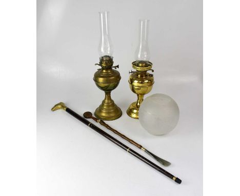 Two brass oil lamps with funnels, one with an etched shade, together with a modern walking stick with brass handle in the for