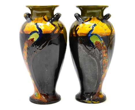 A pair of Victorian/Edwardian Art Nouveau vases, each decorated with a similar peacock and sunset design, possibly Bretby, im