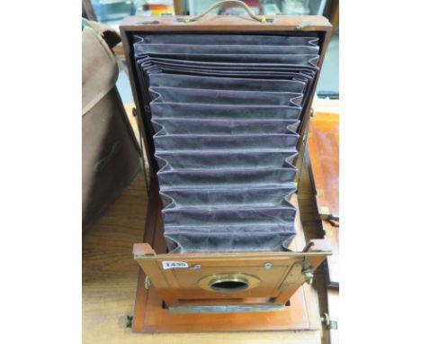 A late Victorian large format mahogany folding plate camera body with maroon bellows - three plate holders and a canvas bag