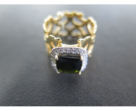 An 18ct yellow gold ring of pierced crossover design with square cut tourmaline to shoulder surrounded by small diamonds ring