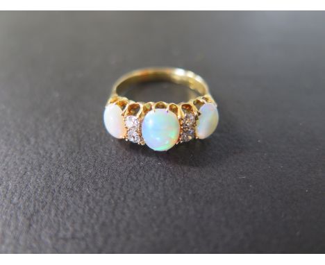 An 18ct yellow gold three stone opal ring set with four small diamonds - ring size Q - approx weight 5.2 grams - central opal