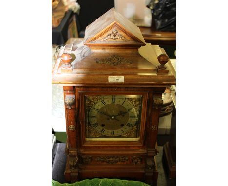 Edwardian walnut and brass mounted mantel clock, the triangular mask decorated pediment flanked by two turned finials, the si