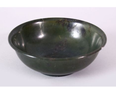 A PLAIN CHINESE CIRCULAR JADE BOWL, with mottled decoration, signed on base, 12cm diameter.