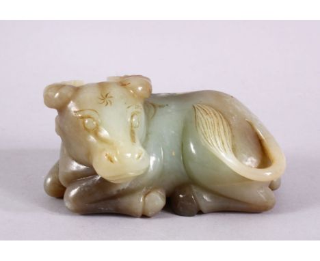 A CHINESE CARVED JADE FIGURE OF A RECUMBENT COW / OX, in a recumbent pose bearing a grin, 12cm wide.