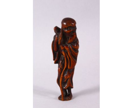 A JAPANESE EDO / MEIJI CARVED BOXWOOD NETSUKE OF A SENNIN,  stood holding his staff, himotoshi formed to the verso, 10cm.