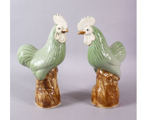 A PAIR OF CHINESE CELADON GLADE PORCELAIN MODEL CHICKENS, each upon a stylized rocky outcrop, with a celadon glaze body,  24.