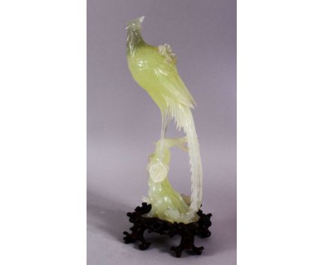 A CHINESE CARVED JADE FIGURE OF A PHOENIX BIRD - stood upon a rocky outcrop, with carved wooden stand, 30cm high ( on stand )