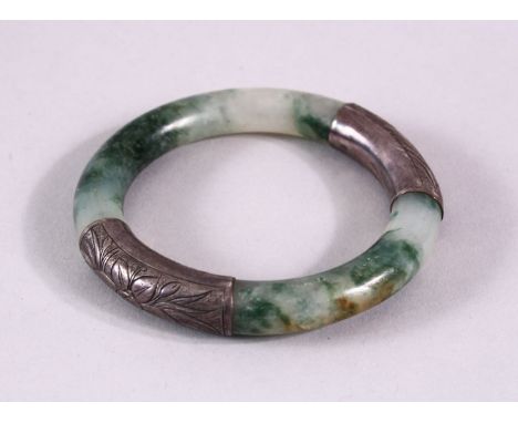 A CHINESE CARVED MOSS GREEN &amp; WHITIE METAL BANGLE, the jade a translucent white with moss green inclusions, with white me