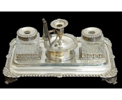 An Edwardian silver desk stand, rectangular tray form with gadrooned border and foliate bracket feet, two floral bordered com