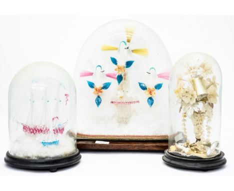A glass makers apprentice example of three decorative birds on a plinth under a glass dome, with a similar glass ship under a