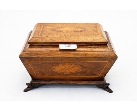 An Edwardian oak sarcophagus shape tea caddy, the hinged cover inlaid with shell paterae
