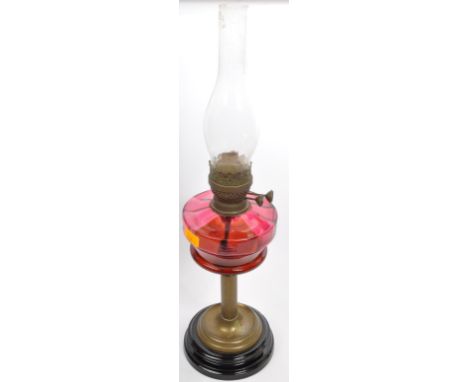 A 19th Century Victorian style cranberry brass oil lamp, having a clear glass flute, with a bulbous circular cranberry red gl