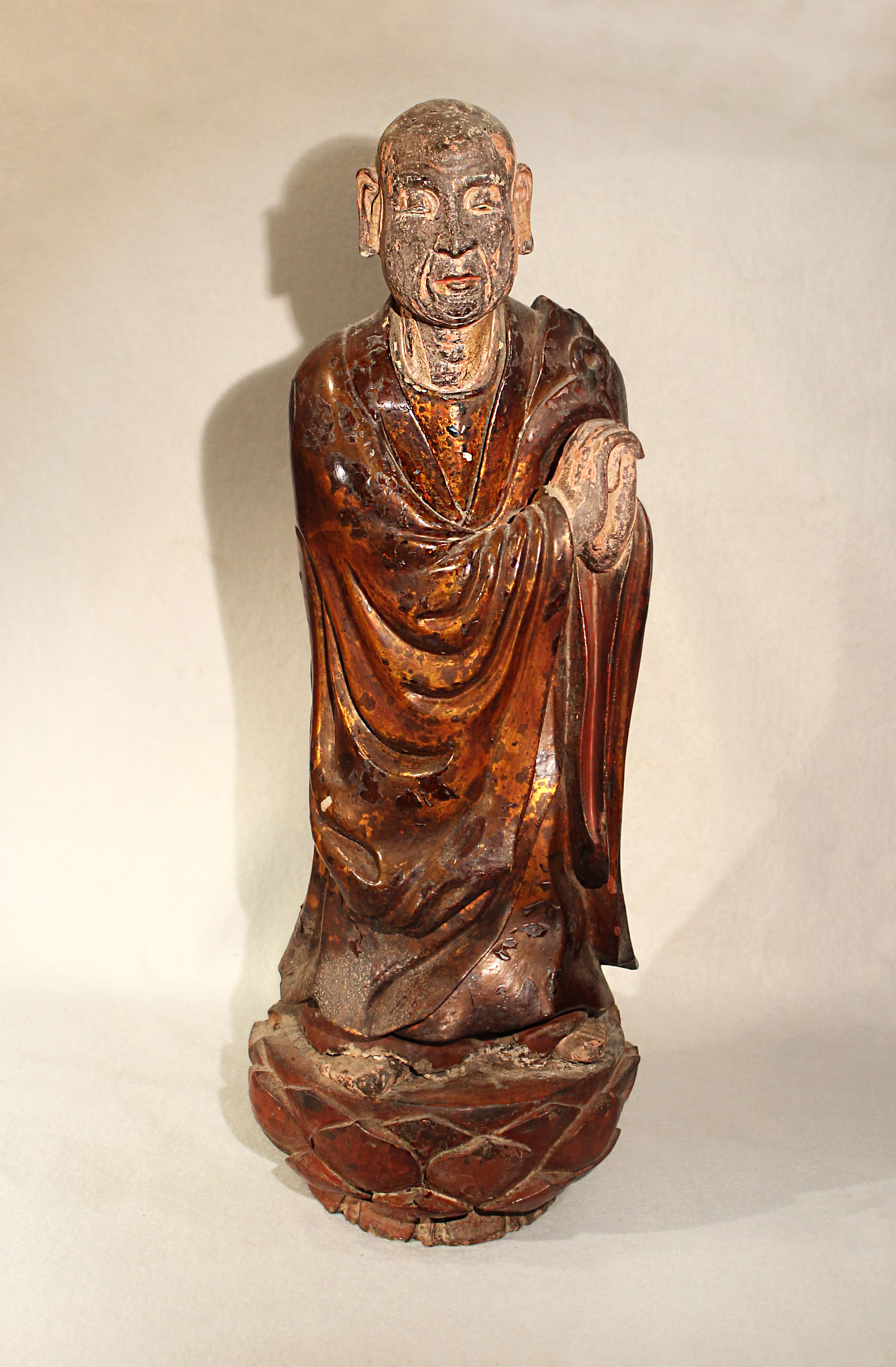 A Chinese lacquered wood figure of a standing lohan, on lotus base, 62.