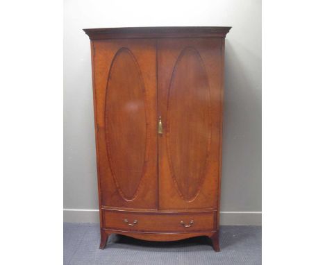 An Edwardian cross banded mahogany bow front two door wardrobe over a base drawer on outswept bracket feet (with key), 193 x 