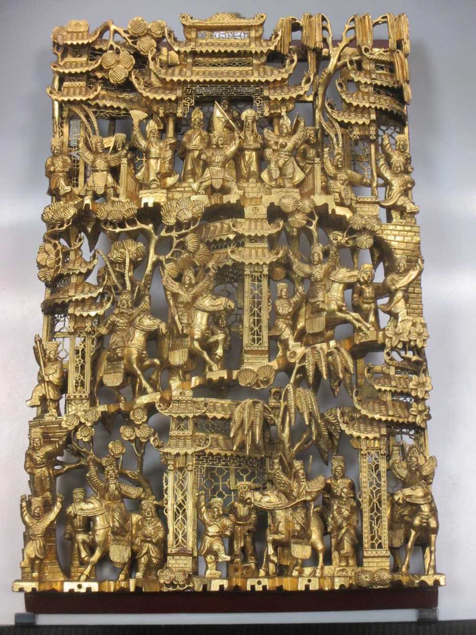 A Chinese gold painted carved wooden panel depicting pagodas and ...