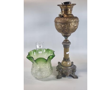 Early 20th century oil burner lamp having green and clear glass shade above a brass repoussé reservoir in a cast metal base. 